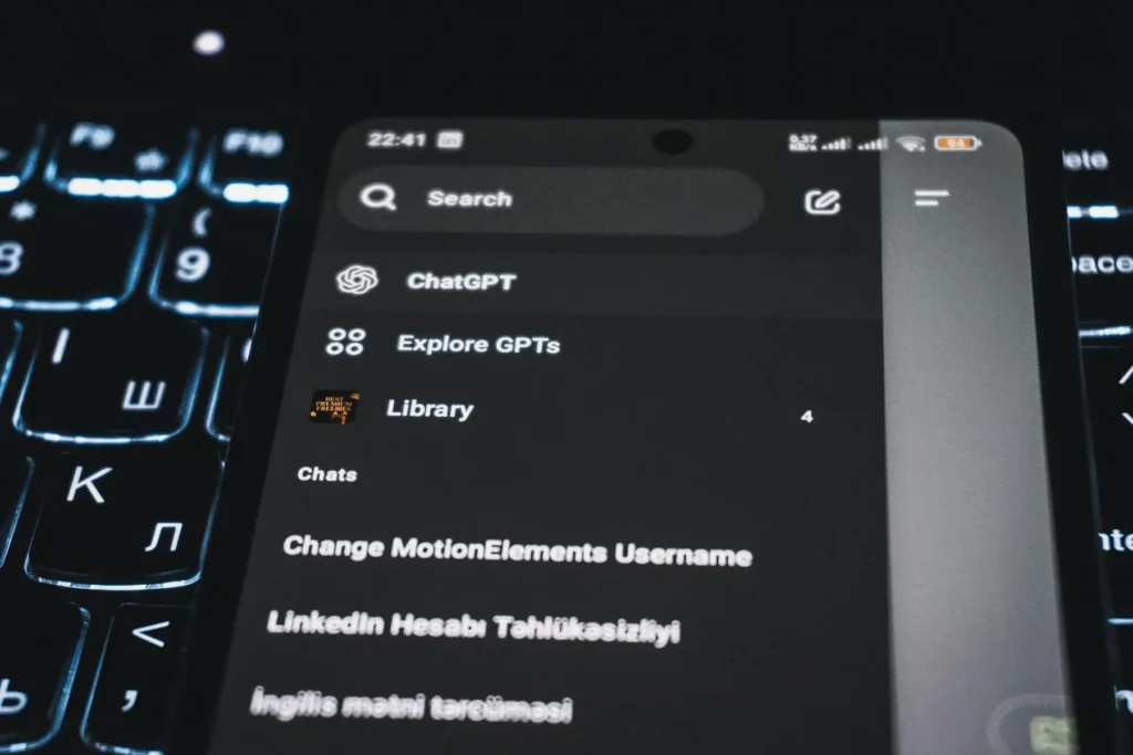 Close-up of a smartphone displaying a chatgpt app interface with a backlit keyboard in the background. Highlights how SEO vs. GEO is the future of small business marketing