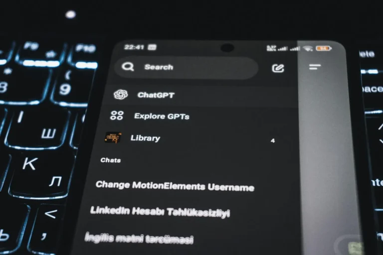 Close-up of a smartphone displaying a chatgpt app interface with a backlit keyboard in the background. Highlights how SEO vs. GEO is the future of small business marketing